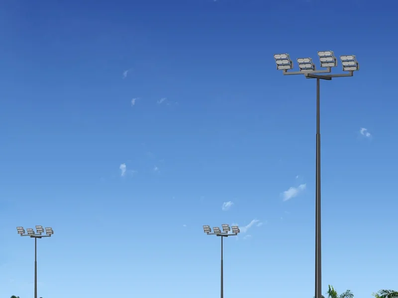 Outdoor tennis courts with tall floodlight masts at the corners, each carrying a cluster of aimed LED floodlights